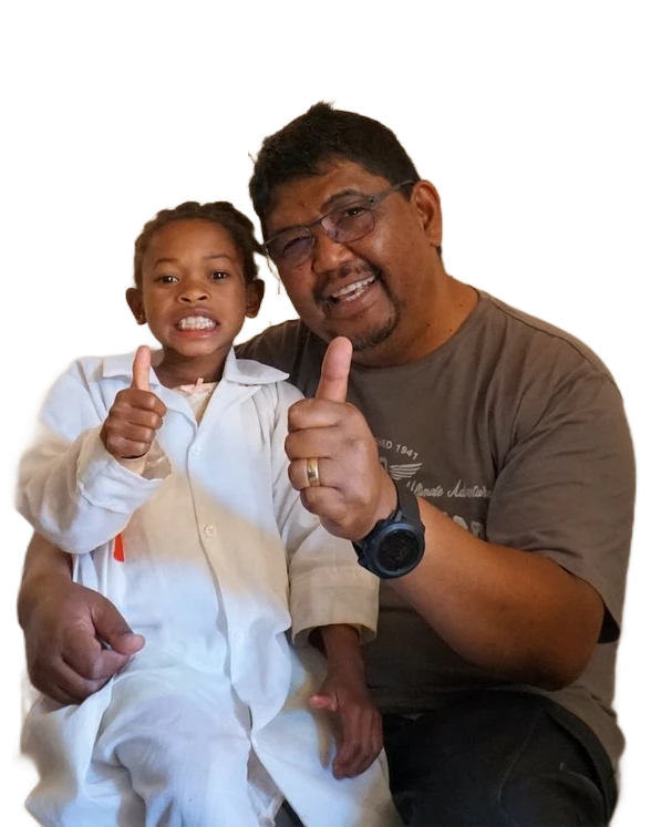 A smiling girl in white and a man, both giving a thumbs up